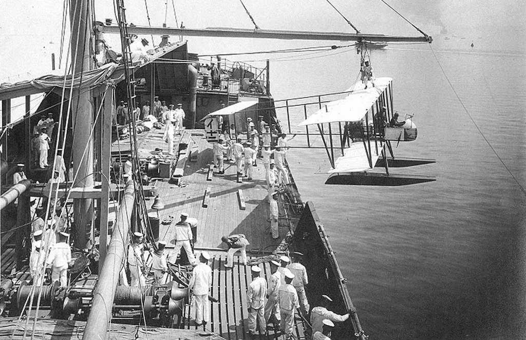 Справедливости ради, первые удары по наземным целям нанесли при осаде немецкой фактории в китайском Циндао осенью 1914-го японские гидропланы с гидроавиатранспорта «Вакамия». Но это был не самостоятельный рейд, а часть осады и штурма крепости. Там же и тогда же немецкий пилот Гюнтер Плюшов впервые в истории сбил самолёт противника в воздушном бою — им стал японский Farman MF.7, который Плюшов умудрился поразить из пистолета за неимением на борту другого оружия. На фото выгрузка на воду гидроплана Farman MF.11 с борта «Вакамия» во время осады Циндао.